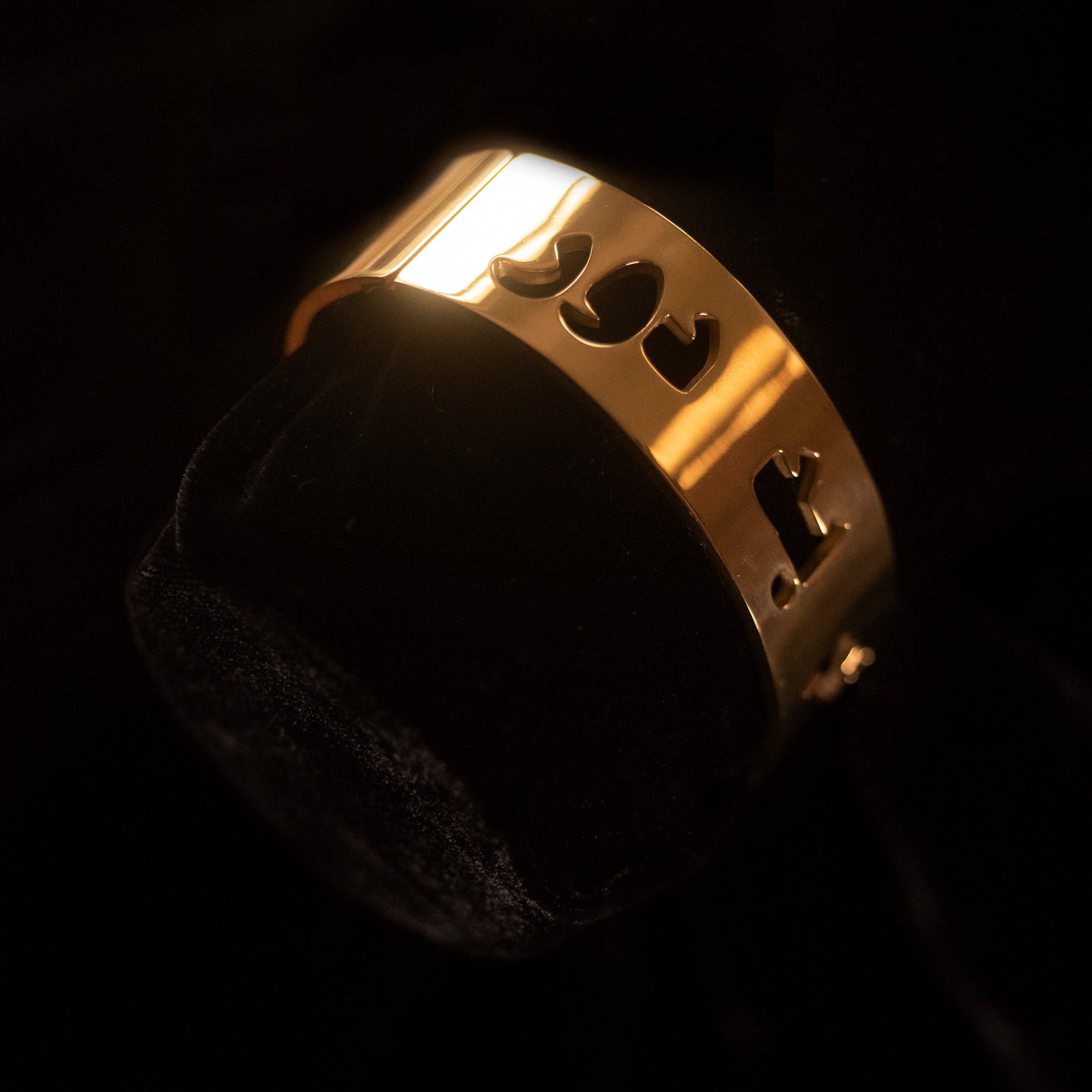A gold bangle against a black background that says Chishme Badh Door in Dari.