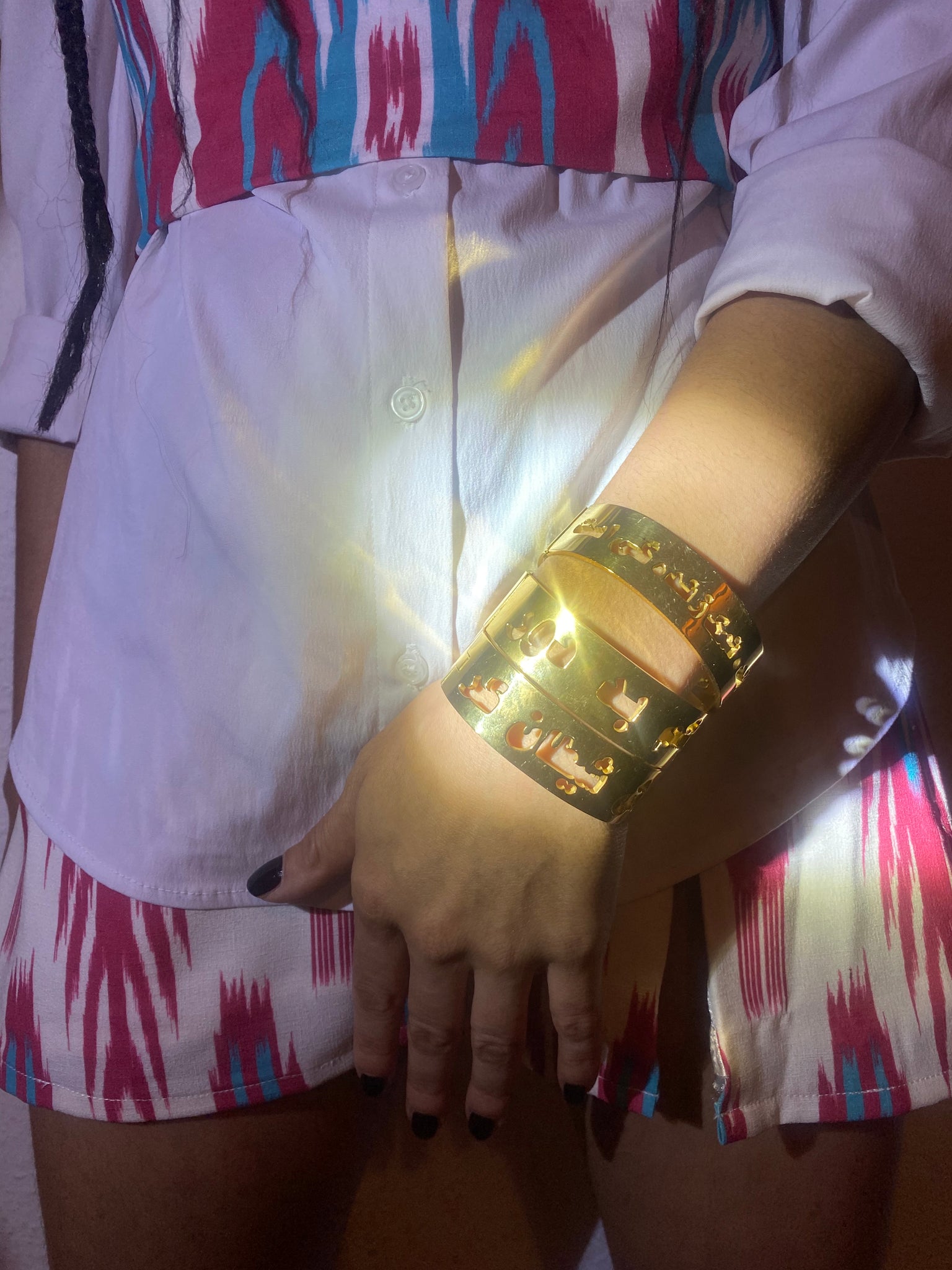 A close up of a woman's hand with three stacked gold bangles.