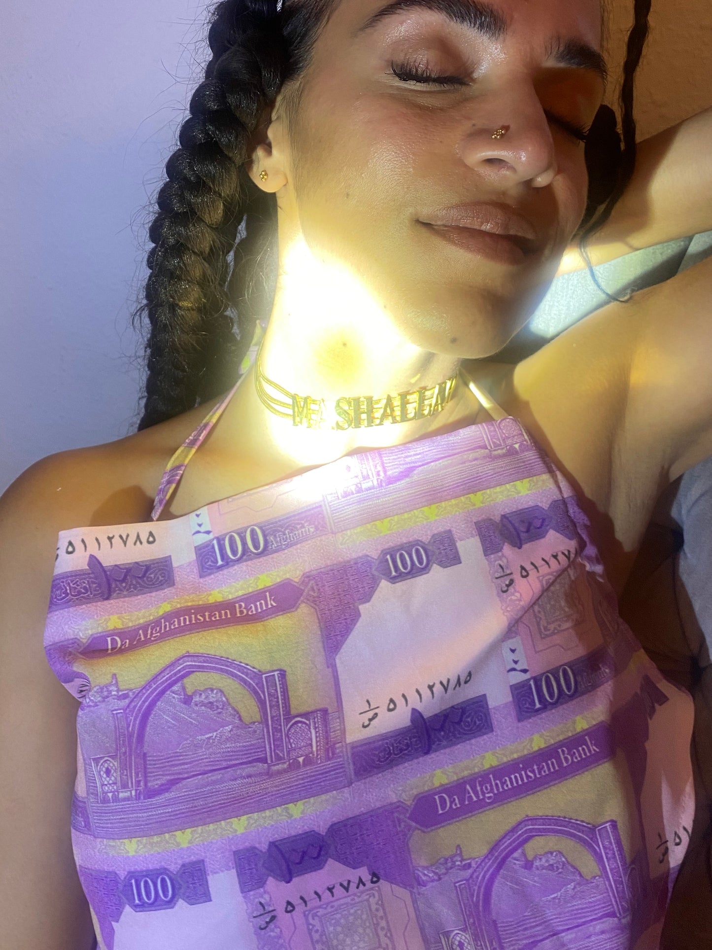 A woman with eyes closed wearing a MashAllah choker.