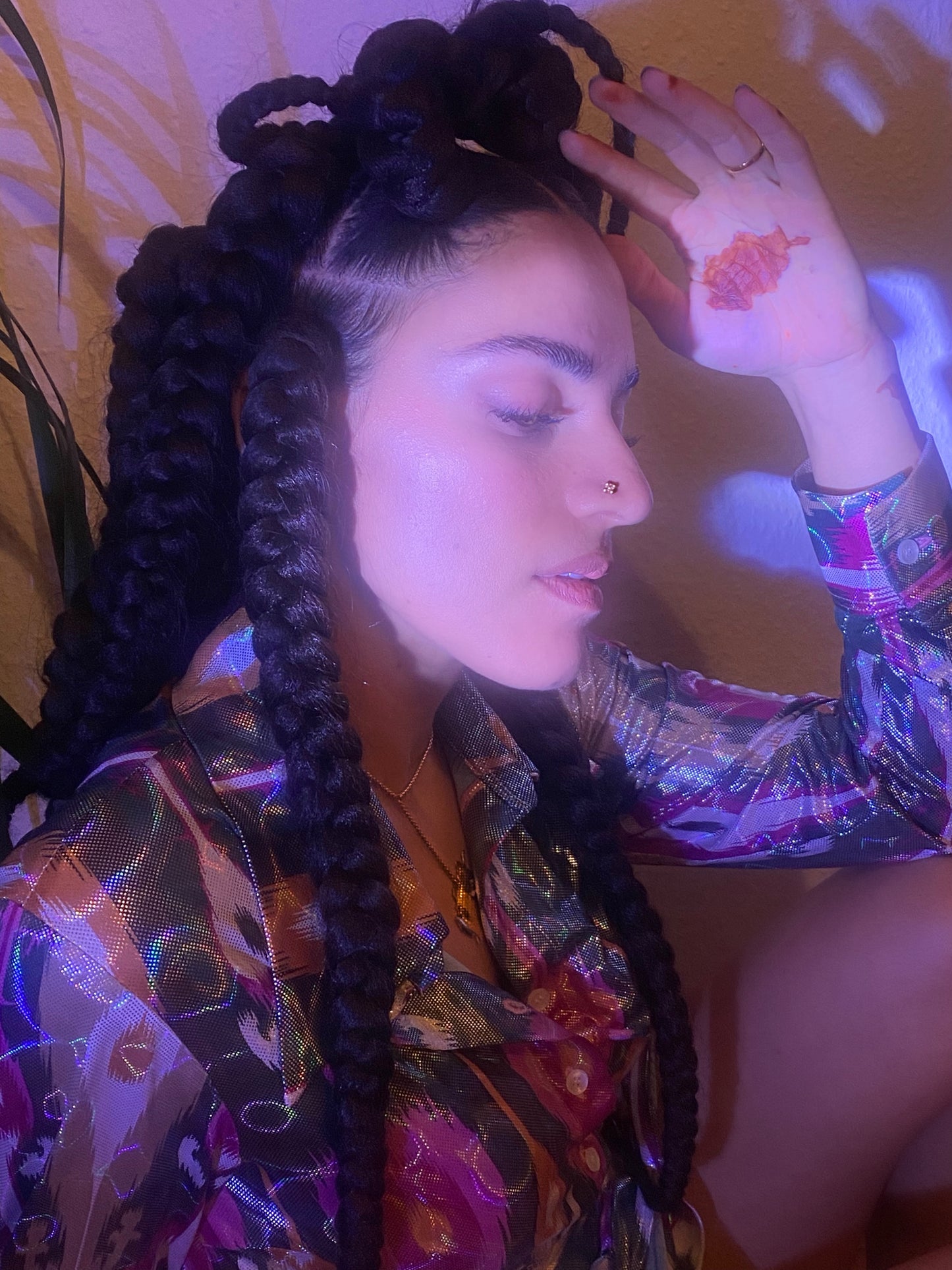 A woman looks down her gold nose stud shining in the light, the map of Afghanistan henna-ed onto her hand.