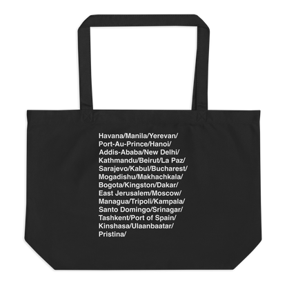 Black tote bag with white text listing various city names on a white background