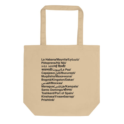 Beige tote bag with black text of cities in their language on a white background