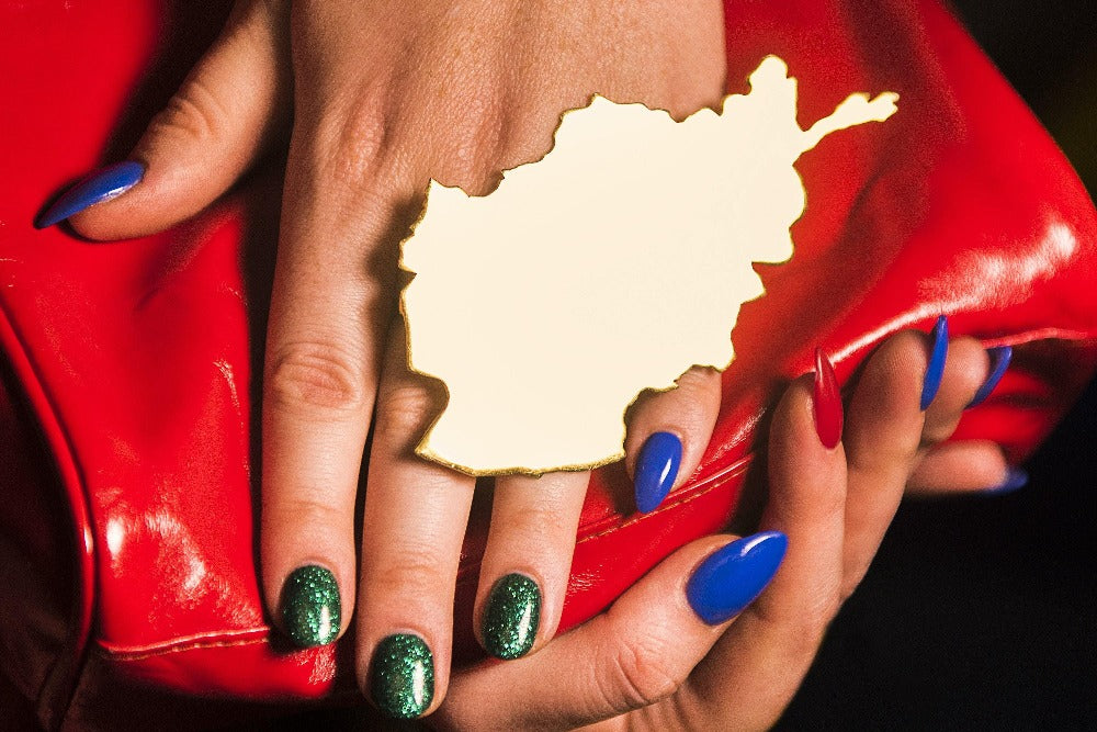 The OG Wataan Three Finger Afghan Map Knuckle Ring - Blingistan, person with blue and green sparkle nails wearing oversized ring.