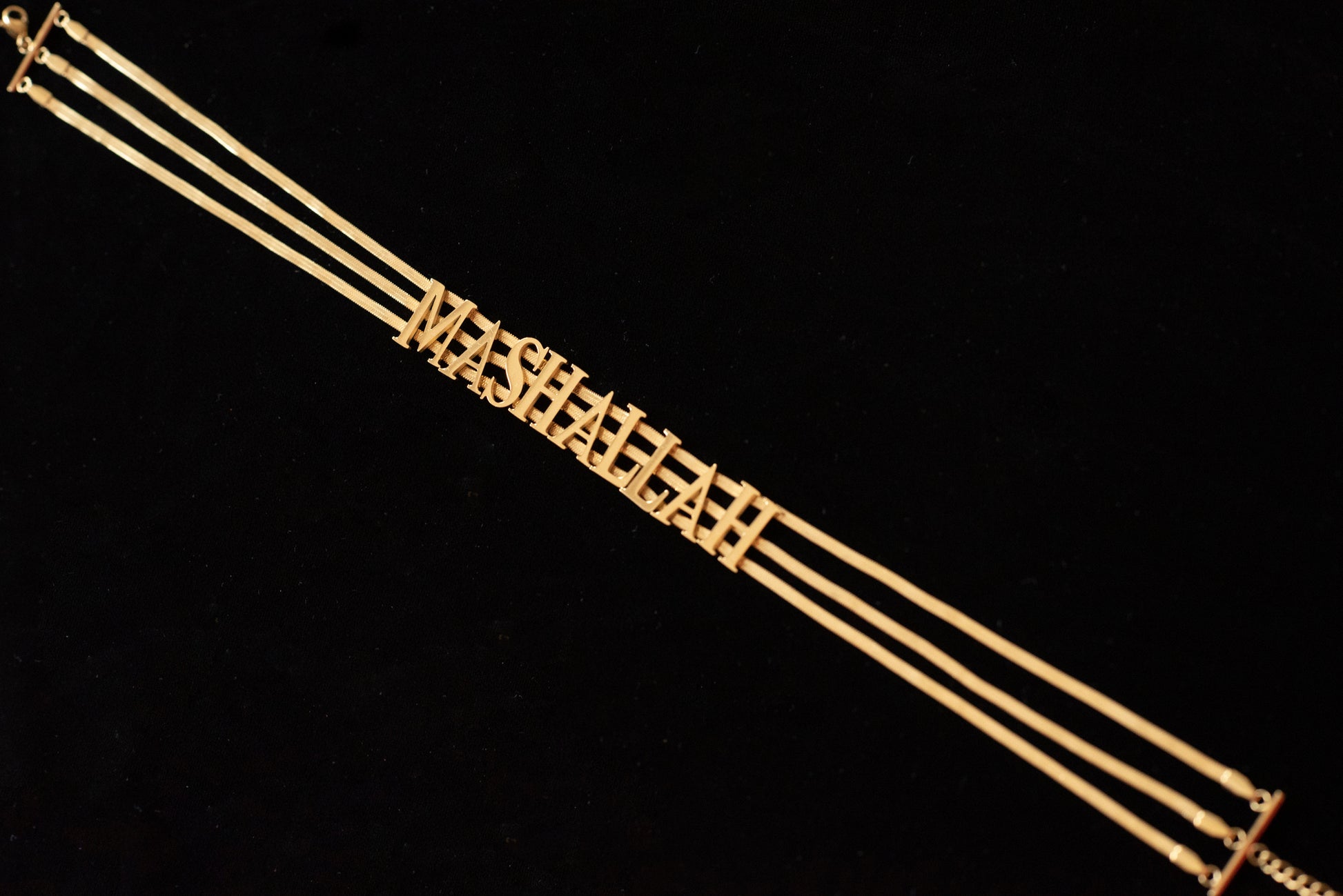 Sideways angle of a choker that says MashAllah in gold.