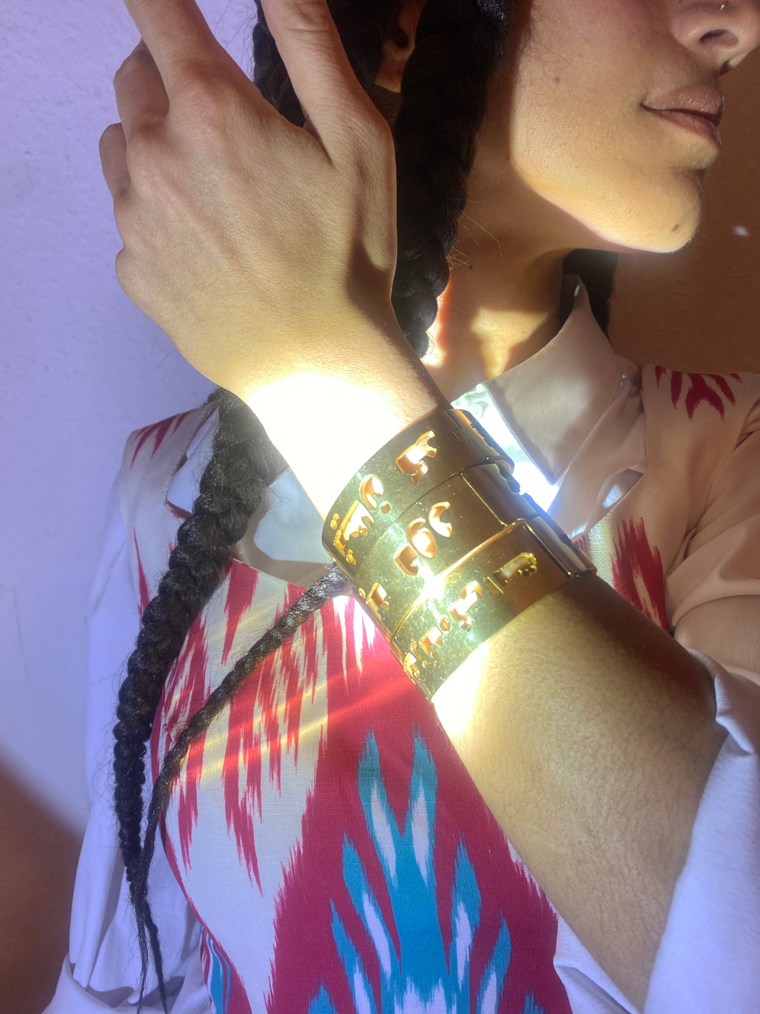 A woman holds up her arm with three gold bangles on.