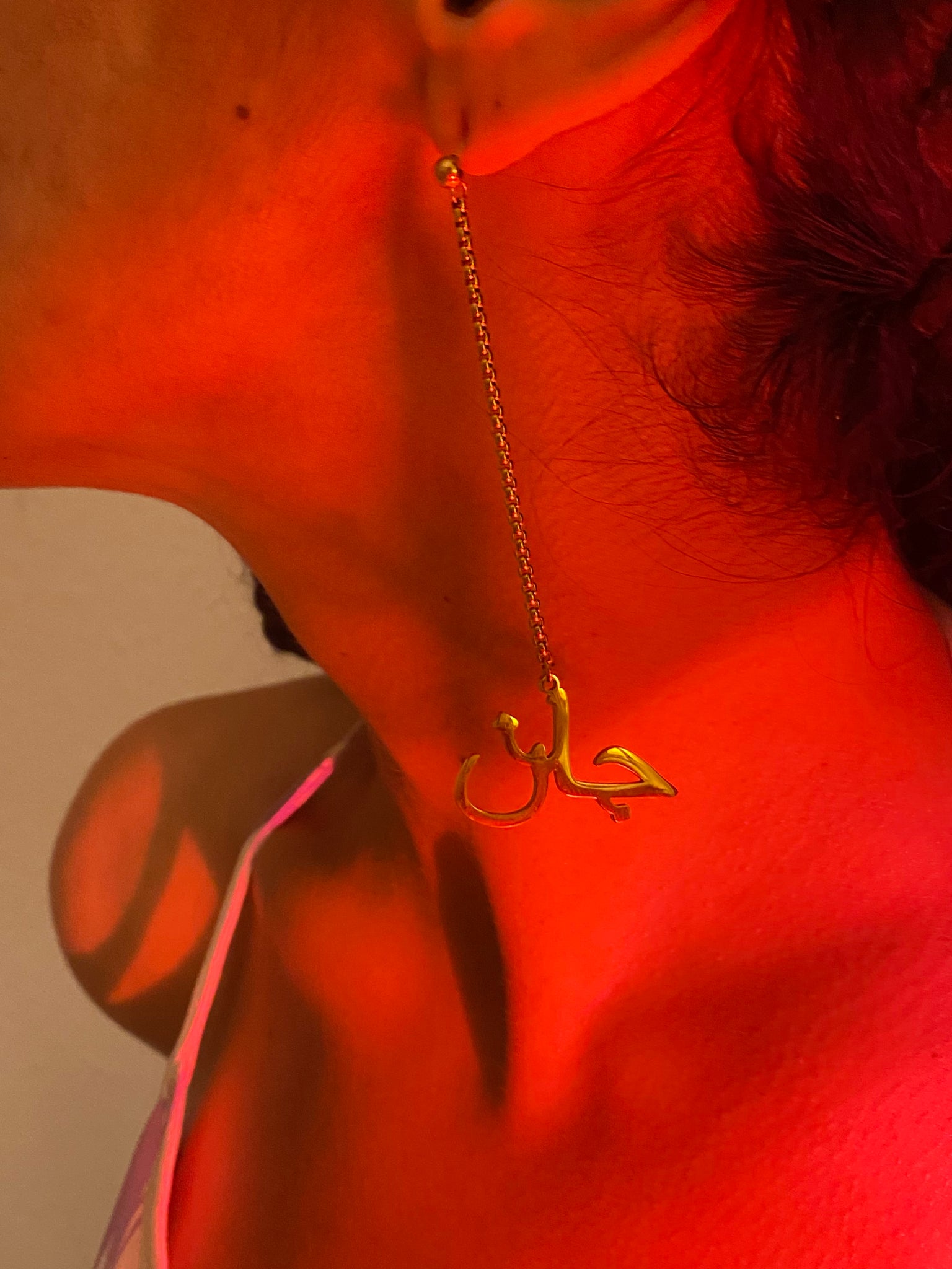A close up of a woman's ear wearing dangly earrings with the word 'jaan' at the bottom.