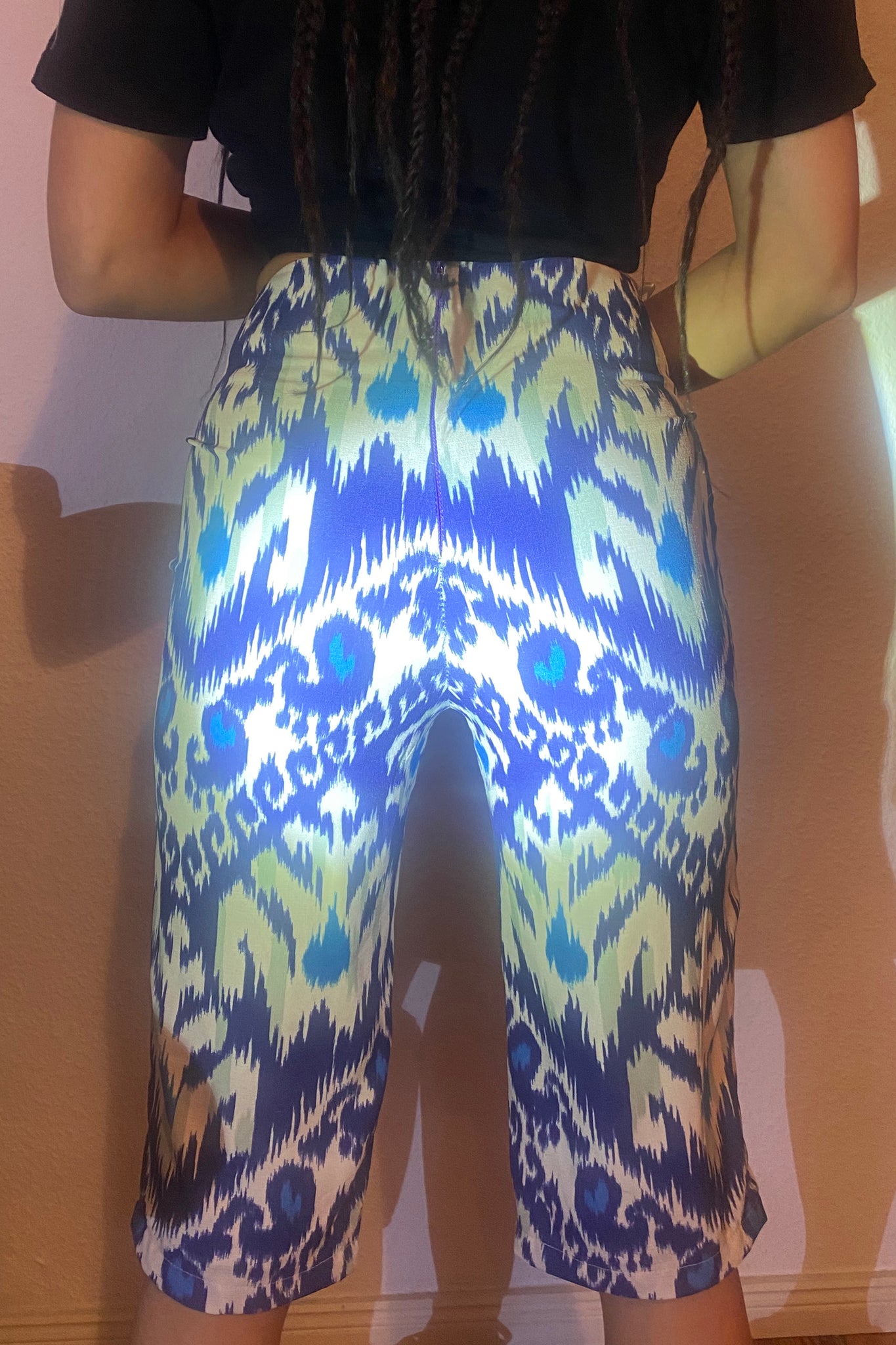 A light shines on the back of adras/ikat capri pants on a body, showing the details of the blues and white fabric.