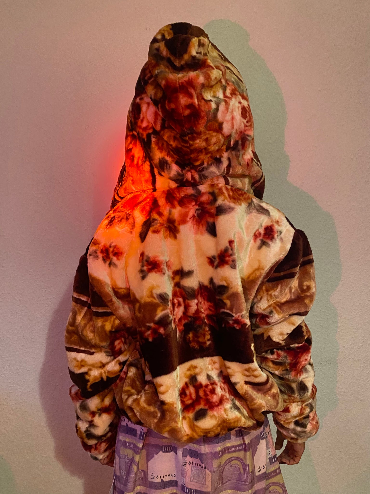 The back of a reversible blanket jacket in brown, tan and cream, with hood up.