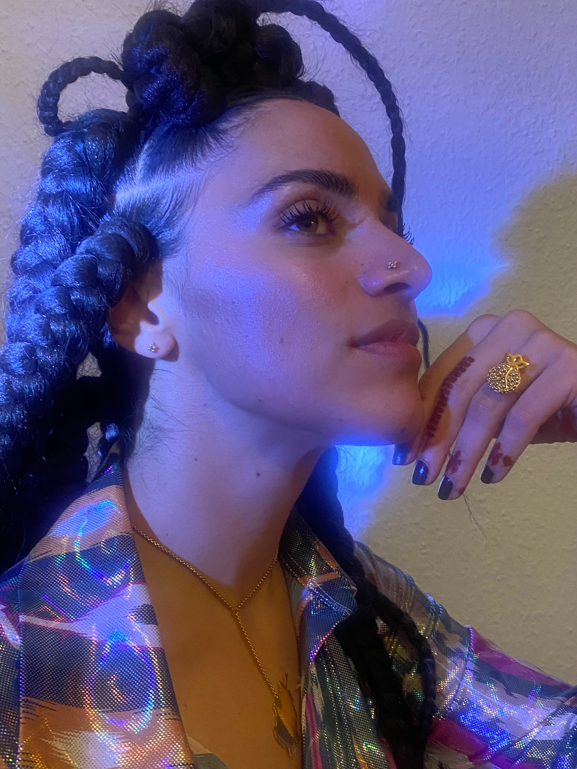 A woman wears a pomegranate shaped ring in gold with a moody blue lighting on her.
