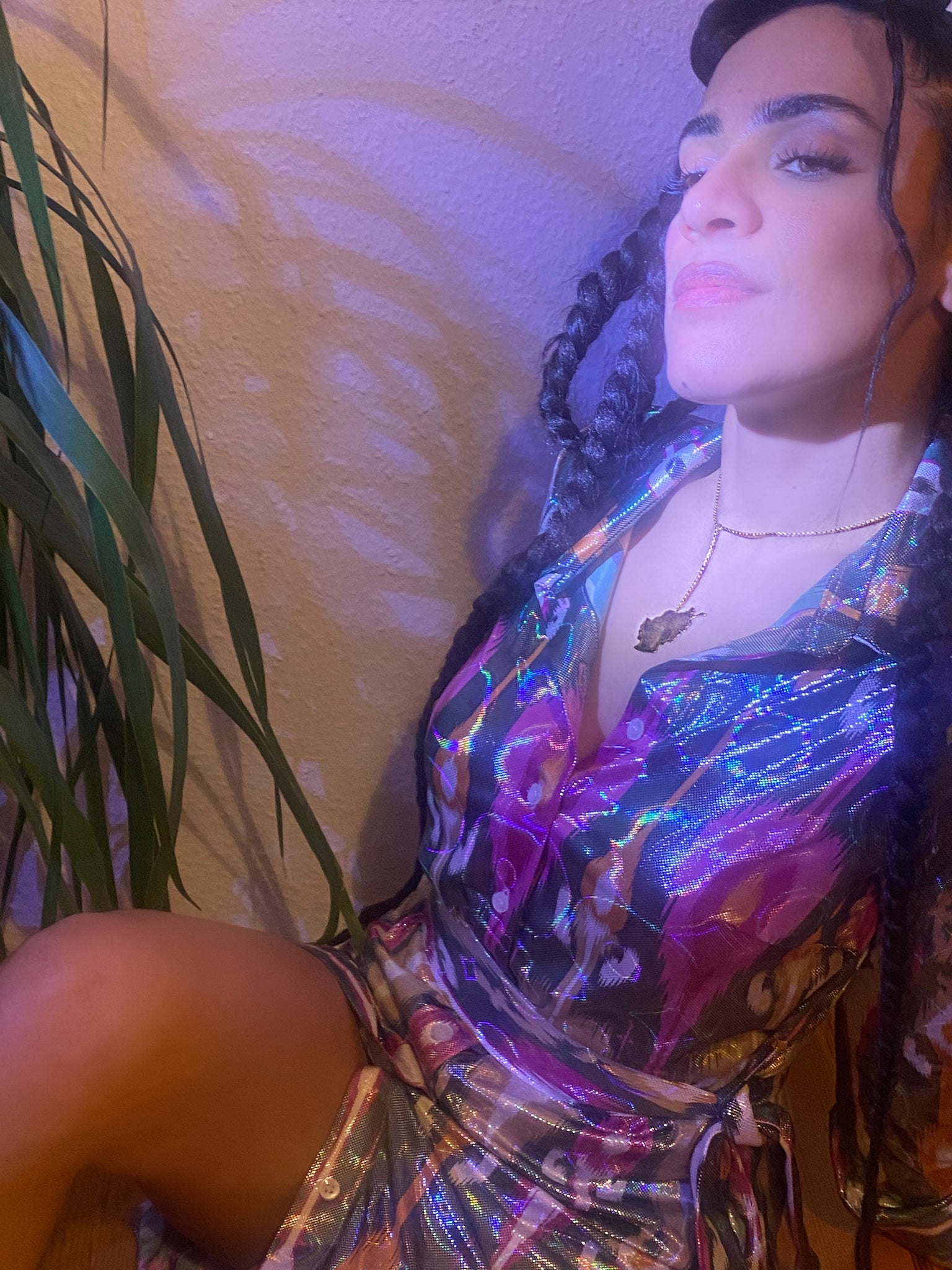 A close up of a woman wearing a green, purple, white, orange holographic dress.